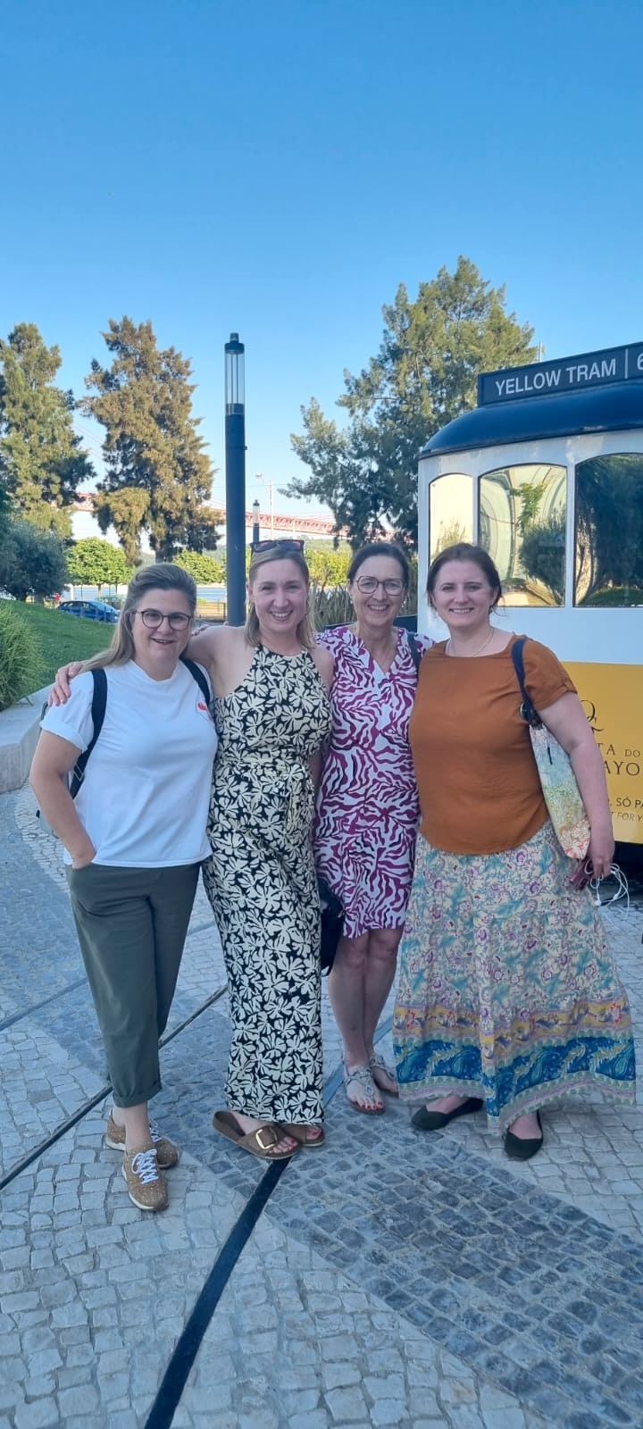 Dr. Vikentia Harizopoulou (UNIWA), Julia Hennicke (Charité – Universitätsmedizin Berlin) and Elisabeth Wilhelm (UNIWA) pose near an iconic yellow Lisbon tram outside of the conference venue
